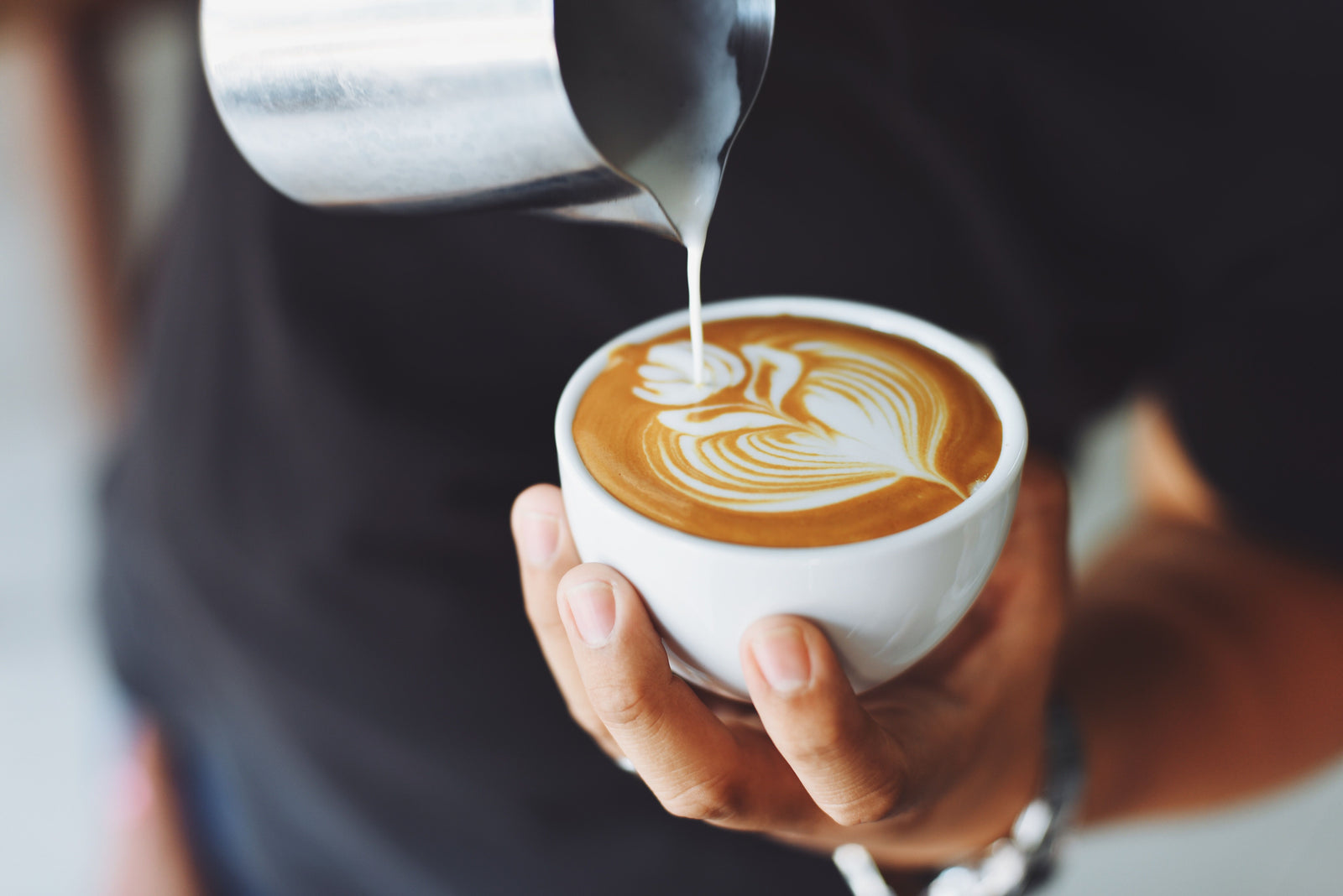 Barista réalisant du latte art dans une tasse de café de spécialité