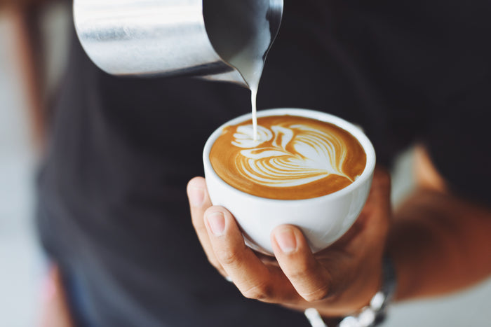 Barista réalisant du latte art dans une tasse de café de spécialité